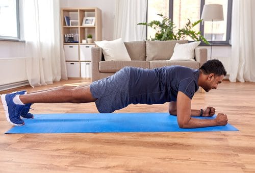 fitness, sport, training and concept - indian man doing plank exercise at home